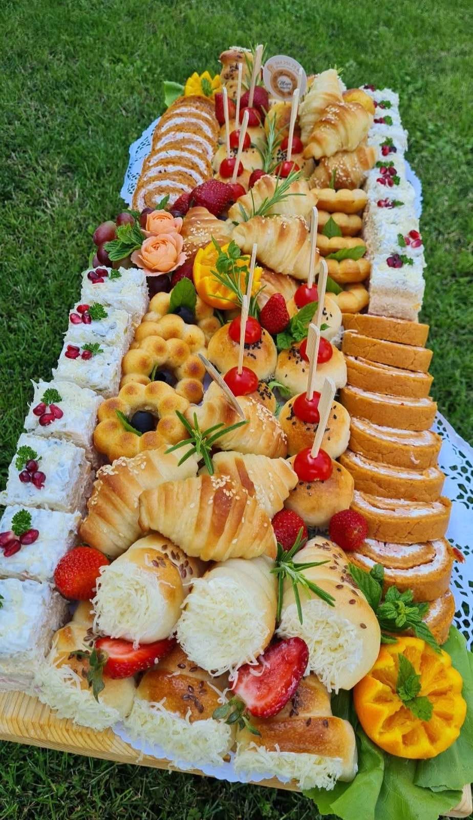 Šareni catering sto na travi sa voćem i pecivima